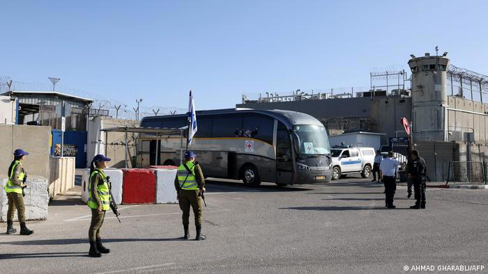 Membros das forças de segurança israelenses montam guarda enquanto um ônibus da Cruz Vermelha Internacional espera para transportar prisioneiros palestinos © Fornecido por IstoÉ