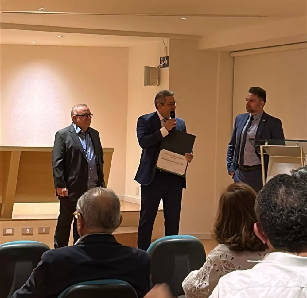 “Dr. Denilson Alencar (à esquerda) é homenageado com o Honra ao Mérito Médico, em Patos-PB, recebendo o diploma das mãos do Dr. Klecius Leite (ao centro), e sendo prestigiado pelo Dr. Bruno Leandro (à direita).”